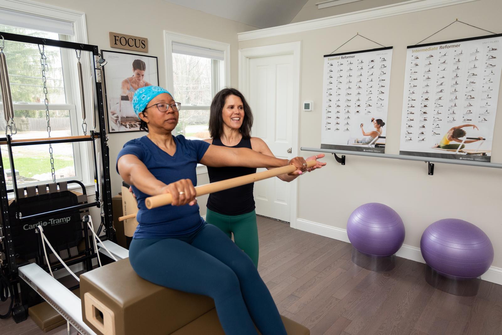 Monica helping a client use the reformer machine